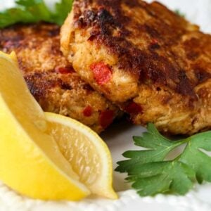 excellent crab cakes on a white plate with sliced lemons
