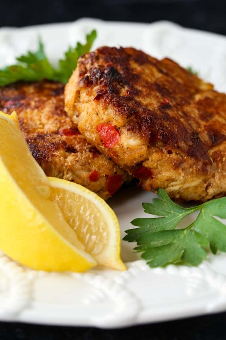 excellent crab cakes on a white plate with sliced lemons