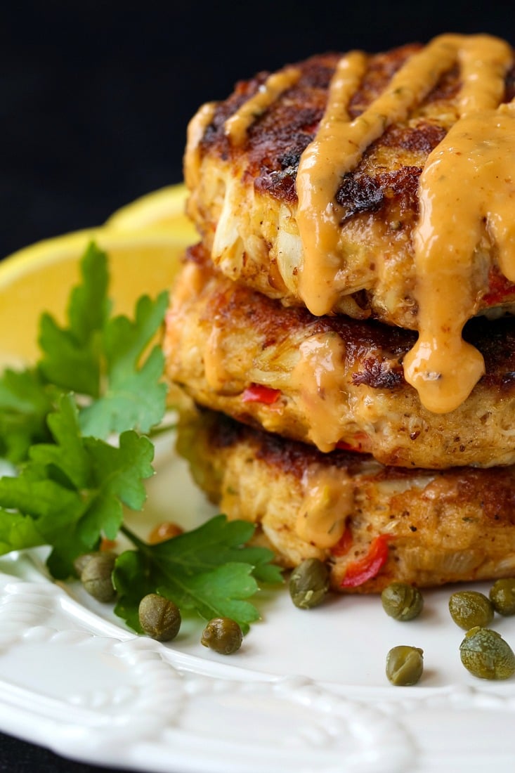crab cakes stacked on a plate with sauce