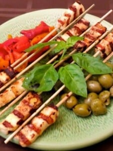 grilled halloumi cheese kabobs on plate with olives