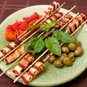 grilled halloumi cheese kabobs on plate with olives