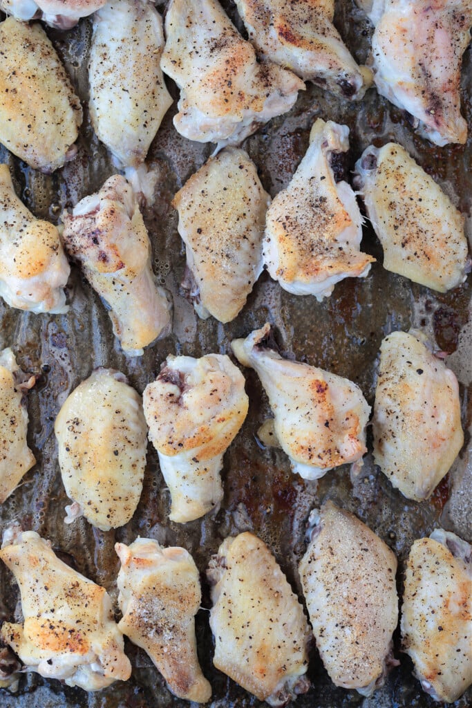 These Asian Chicken Wings are oven baked until tender, with a sticky, sweet addicting sauce. Perfect for appetizers or a fun dinner! cooked chicken wings on baking sheet