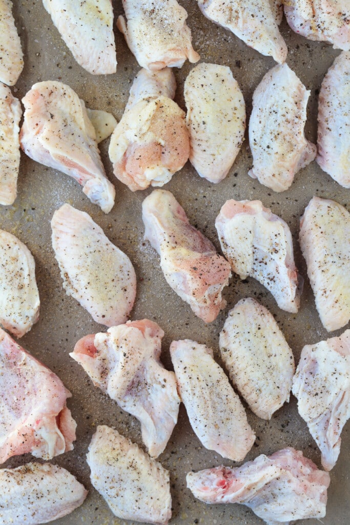 These Asian Chicken Wings are oven baked until tender, with a sticky, sweet addicting sauce. Perfect for appetizers or a fun dinner! uncooked chicken wings on sheet pan