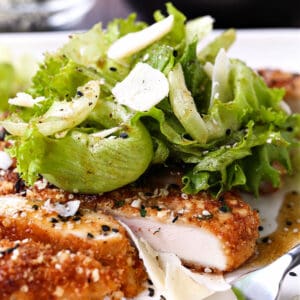 Sesame Chicken Milanese on a white plate with fork