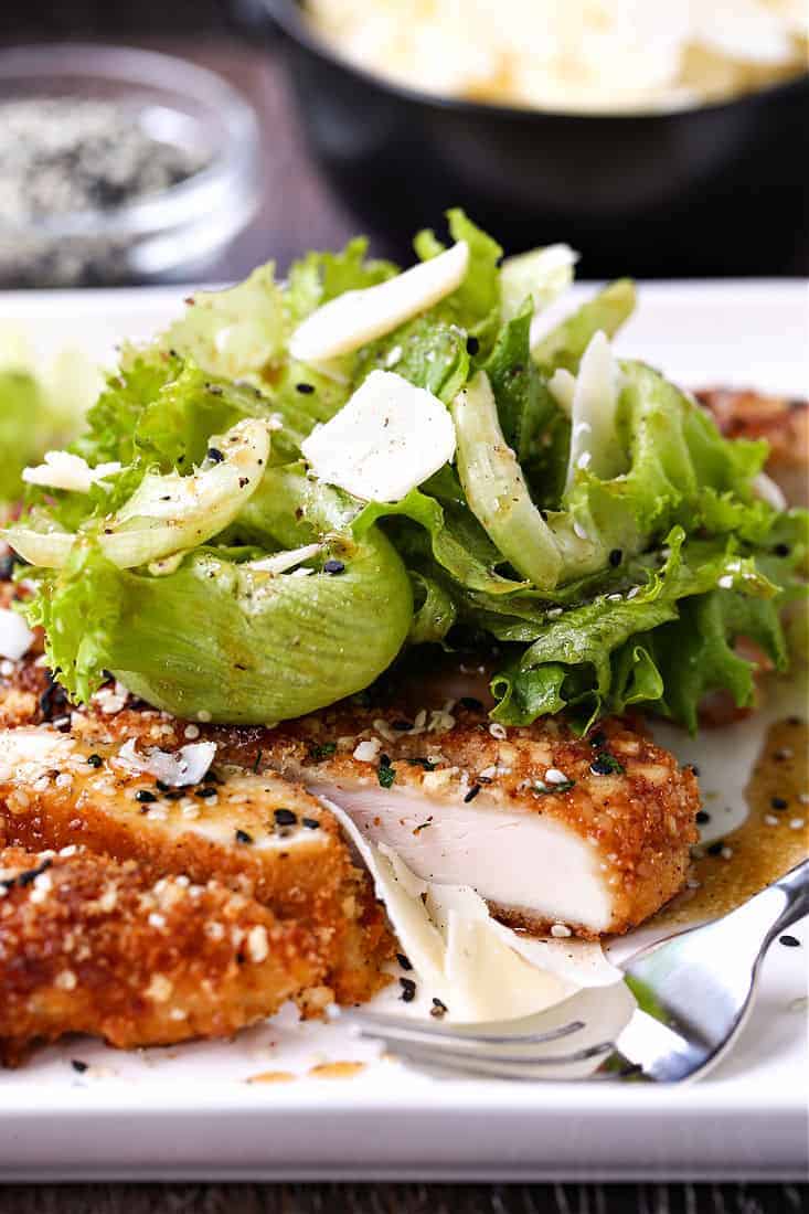 Sesame Chicken Milanese on a white plate with fork