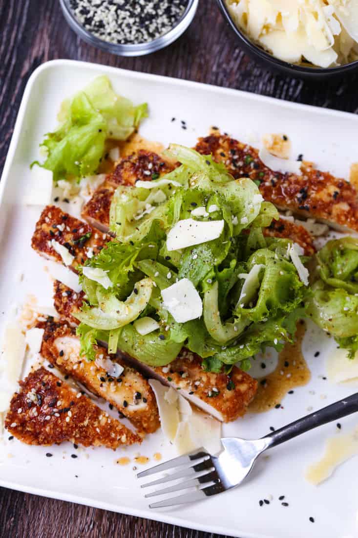 Sesame Chicken Milanese is a delicious twist on the classic chicken recipe! Thin, crispy chicken cutlets topped with crisp greens and an Asian vinaigrette! Chicken Milanese topped with an Asian tossed salad