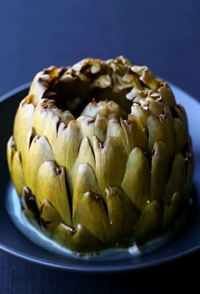 Stuffed Cheesy Garlic Artichokes on a black plate