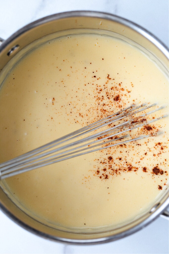 mornay sauce in pot with whisk and grated nutmeg