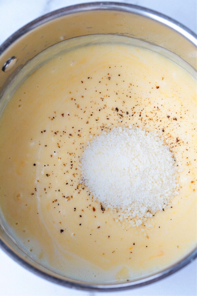 grated parmesan cheese in a pot with cheese sauce