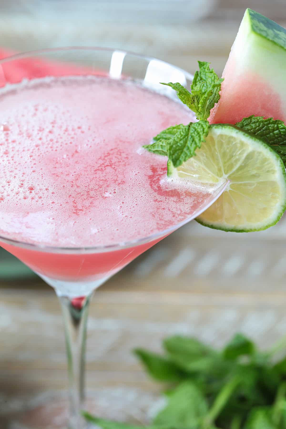 This Watermelon Cosmopolitan is the ultimate summer drink! So light and refreshing, made with fresh watermelon juice and a hint of lime! top shot of a cosmopolitan with lime and watermelon garnish