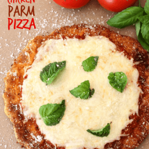 Chicken Parm Pizza on a pizza stone with tomatoes and fresh basil