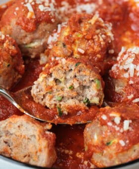 a cut turkey zucchini meatball on a spoon with sauce