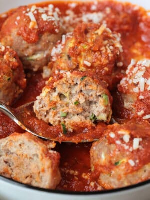 a cut turkey zucchini meatball on a spoon with sauce