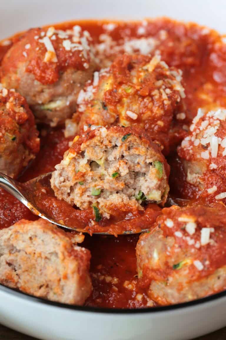 a cut turkey zucchini meatball on a spoon with sauce