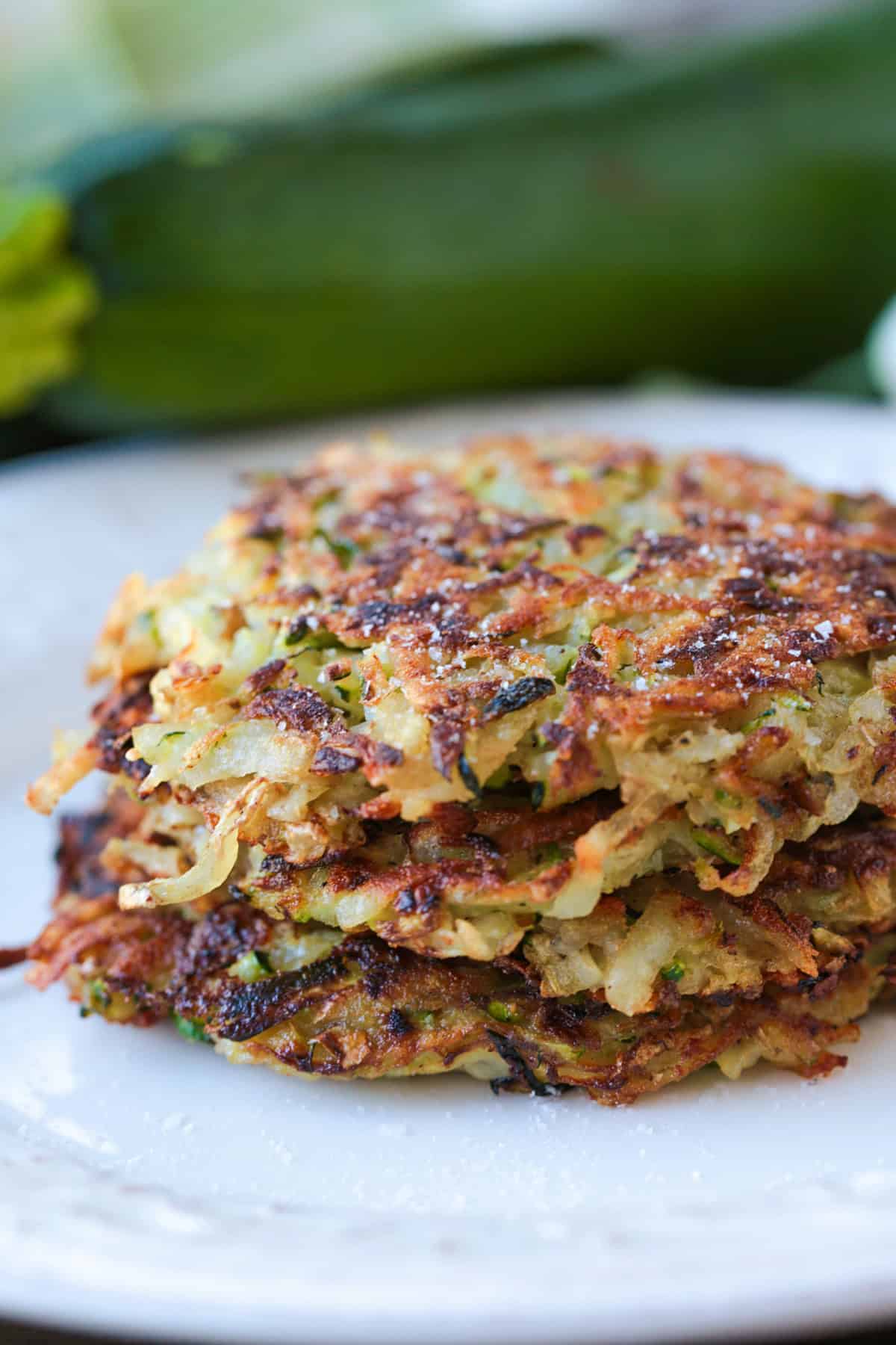 zucchini hash browns stacked on a white plate