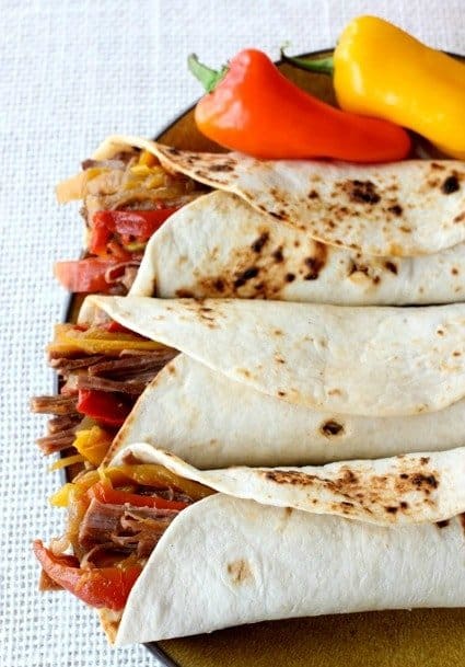 Fajita filling rolled up in toasted tortilla shells with peppers