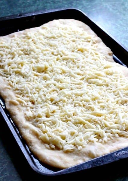 This Italian Beef Pizza has all the flavors of an Italian Beef Sandwich baked on a pizza! A fun recipe to serve at game days and parties! pizza crust with mozzarella cheese on baking sheet