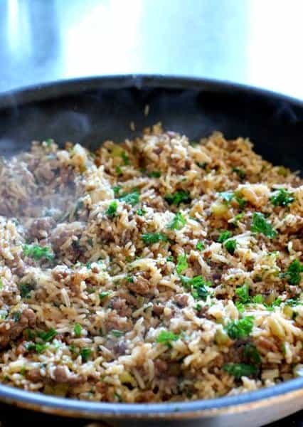 Our Easy Dirty Rice Recipe is done in about 30 minutes! A hearty, classic rice recipe that can be served as a side or even a main course! rice, sausage and ground beef in a skillet