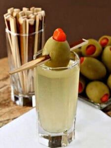 single shot on napkin with olive garnish