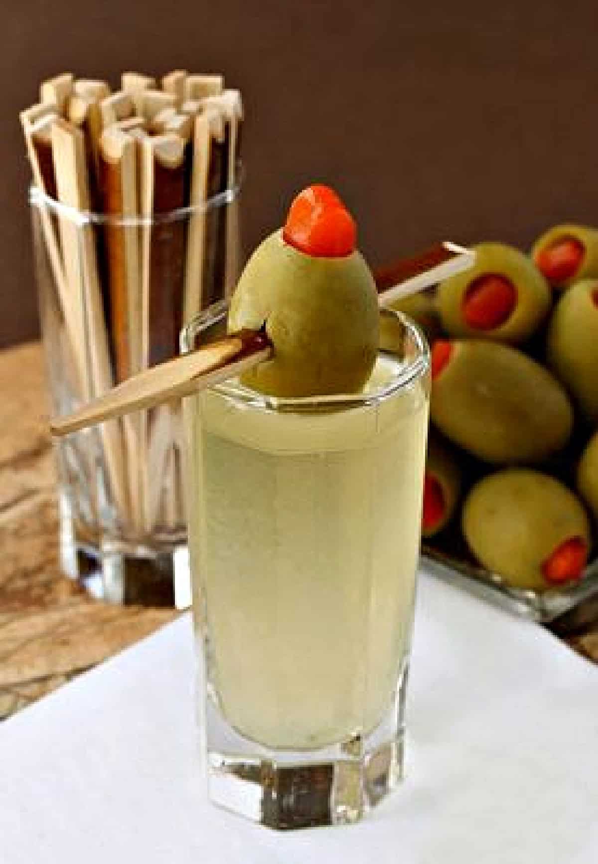 single shot on napkin with olive garnish