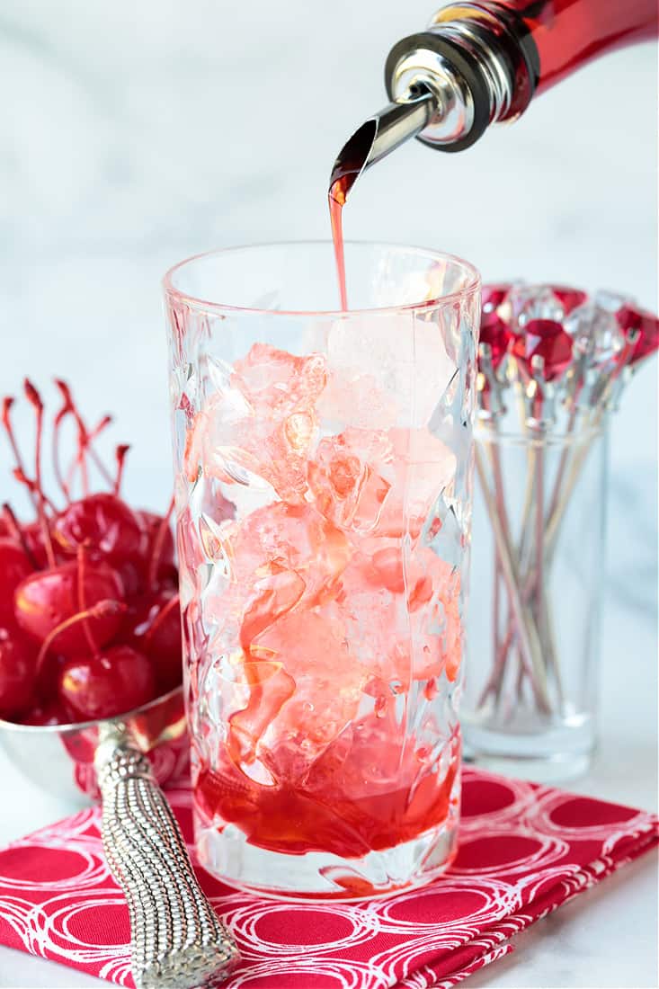 Grenadine being poured into a highball glass