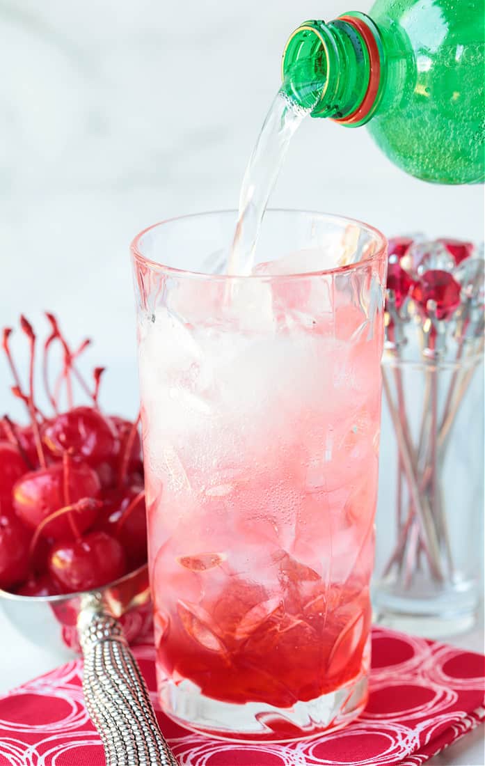 Lime soda bring poured into a high ball glass with vodka and grenadine
