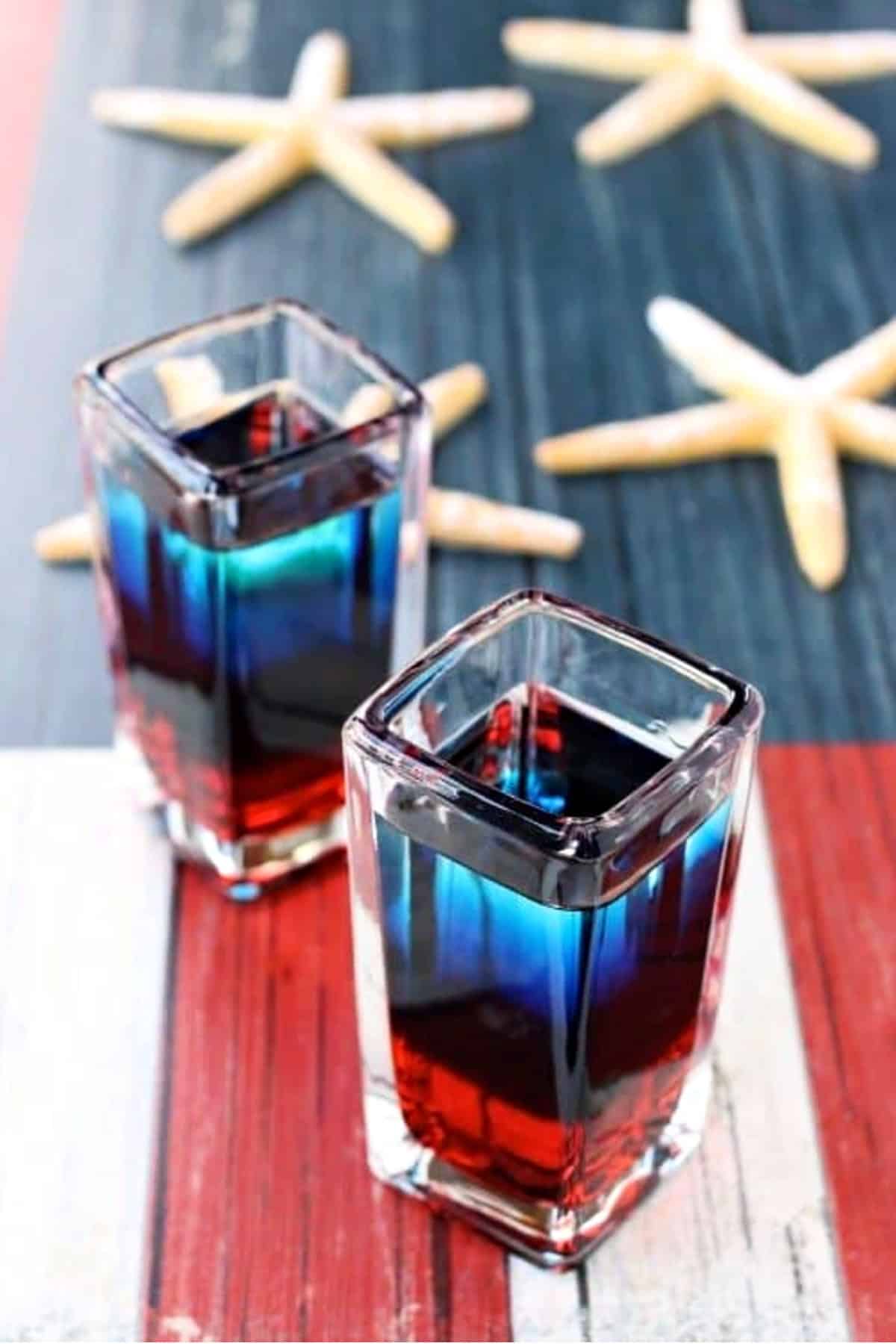 Make up a batch of these Red White and Blue Shooters for your BBQ parties this summer! Everyone is going to love these patriotic vodka shots! layered red, white and blue shots on flag board