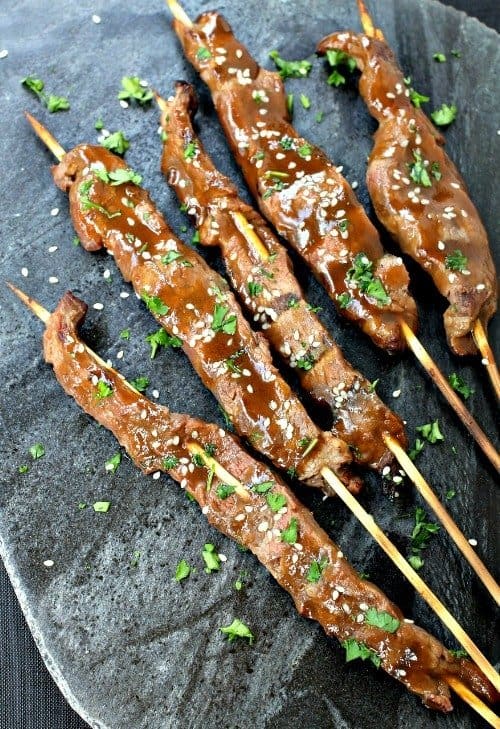 Five steak kabobs on a rock slab