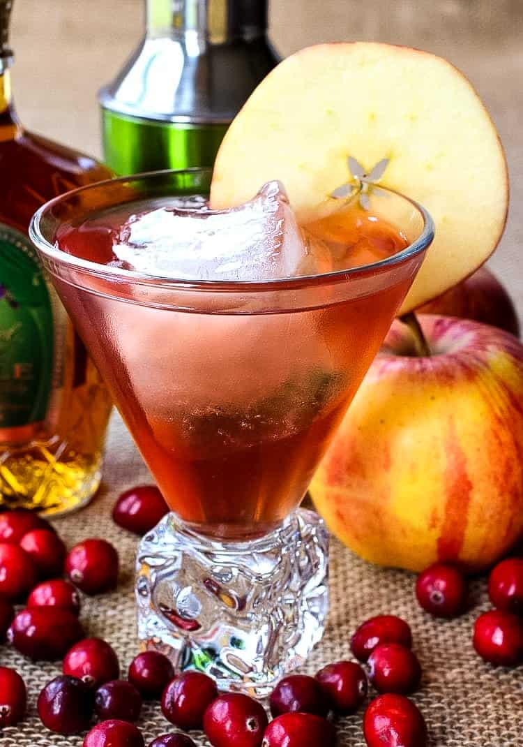 Crown Royal Apple cocktail in a glass with an apple slice and surrounded by cranberries 