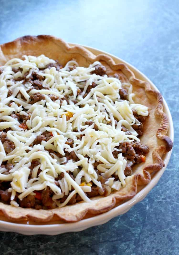 An uncooked Taco Pie filled with beef and cheese 