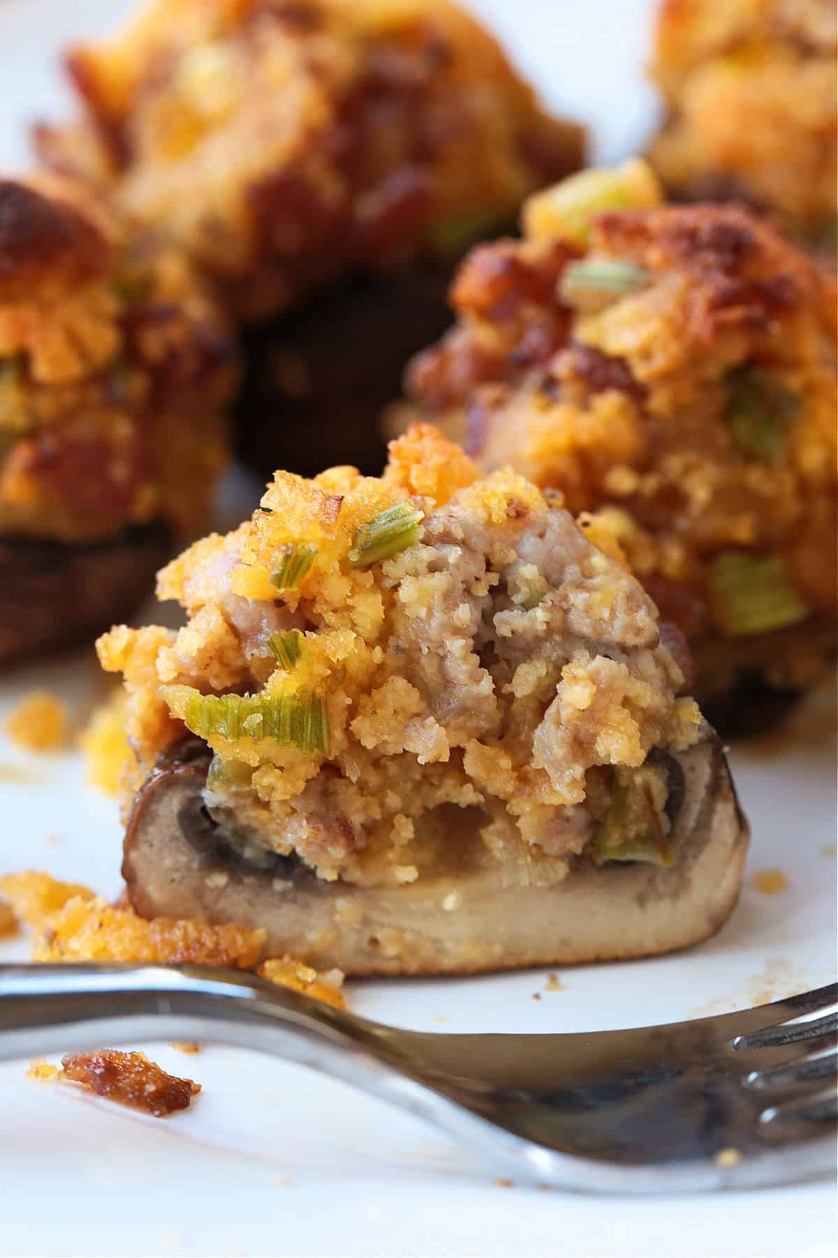 fork on a plate with a stuffed mushroom cut in half
