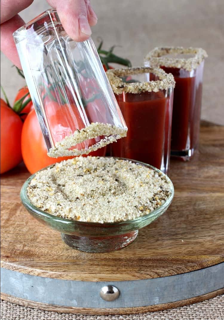 These Winey Mary Shooters are a fun twist on a Bloody Mary! A Bloody Mary shot made with red wine that's perfect for game days and brunch! shot glass being dipped into rimming salt