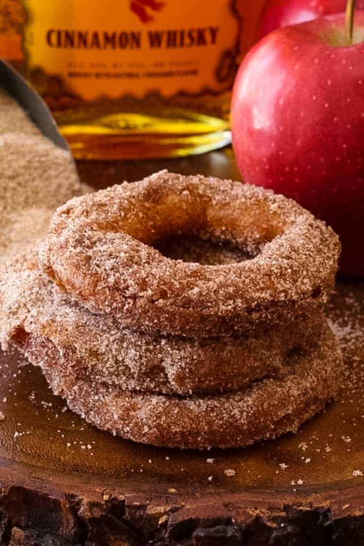 Fireball Apple Fritters are the ultimate party dessert! Fresh apple fritters coated in a cinnamon whiskey batter tossed with cinnamon sugar. fireball apple fritters recipe on a board