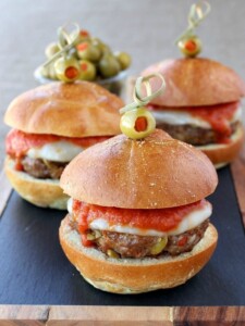 sausage sliders on board with toothpicks holding green olives