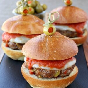 sausage sliders on board with toothpicks holding green olives