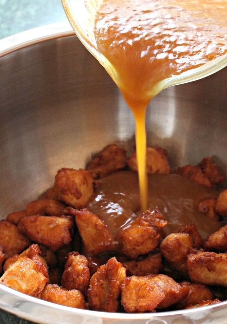 orange sauce being poured over orange chicken