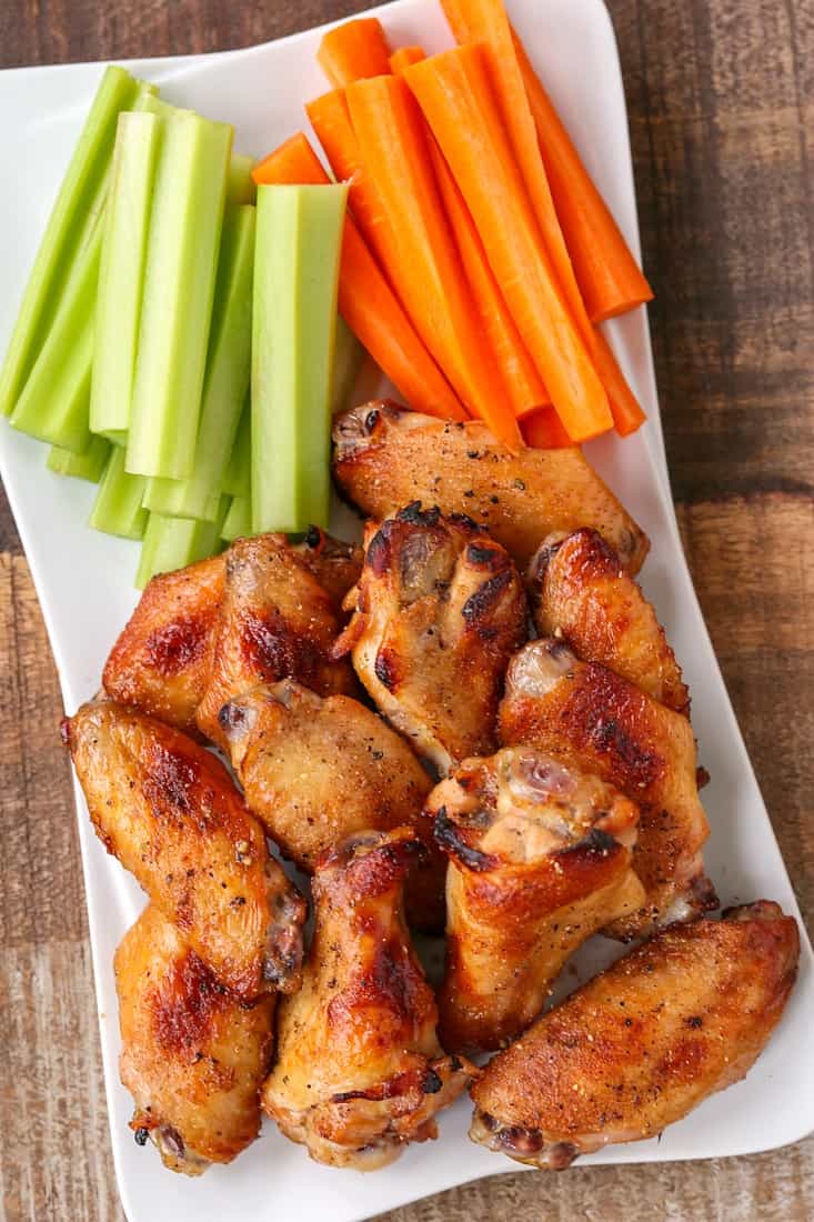 Baked chicken wings with carrots and celery on a platter