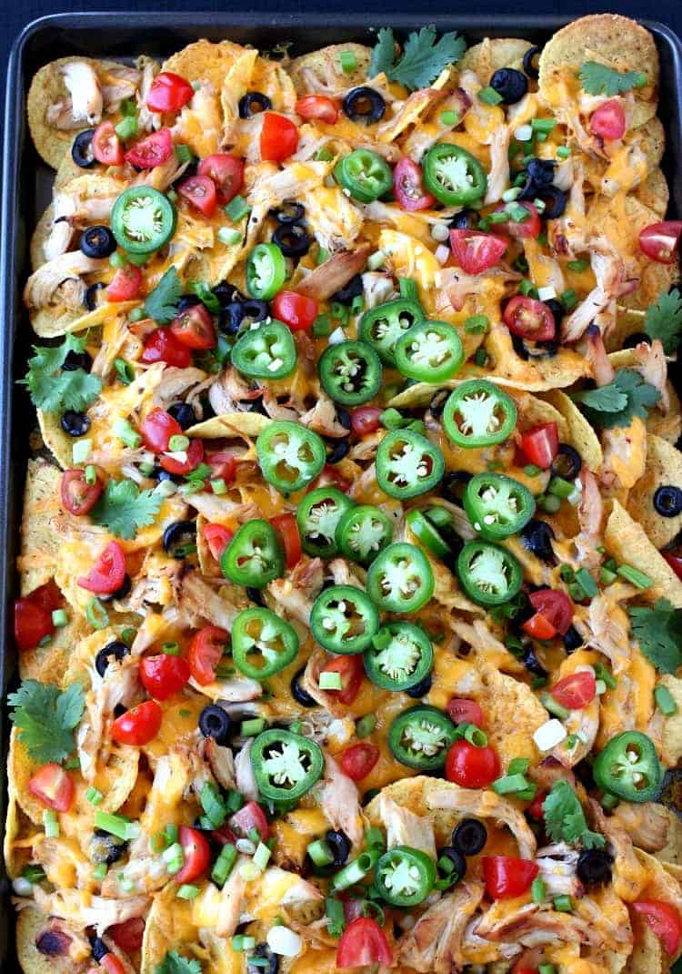 sheet pan chicken nachos with toppings from the top view