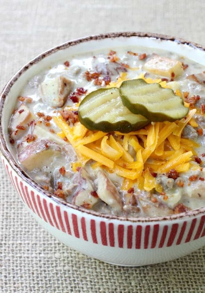Cheeseburger and Fries Soup recipe in a bowl topped with pickles