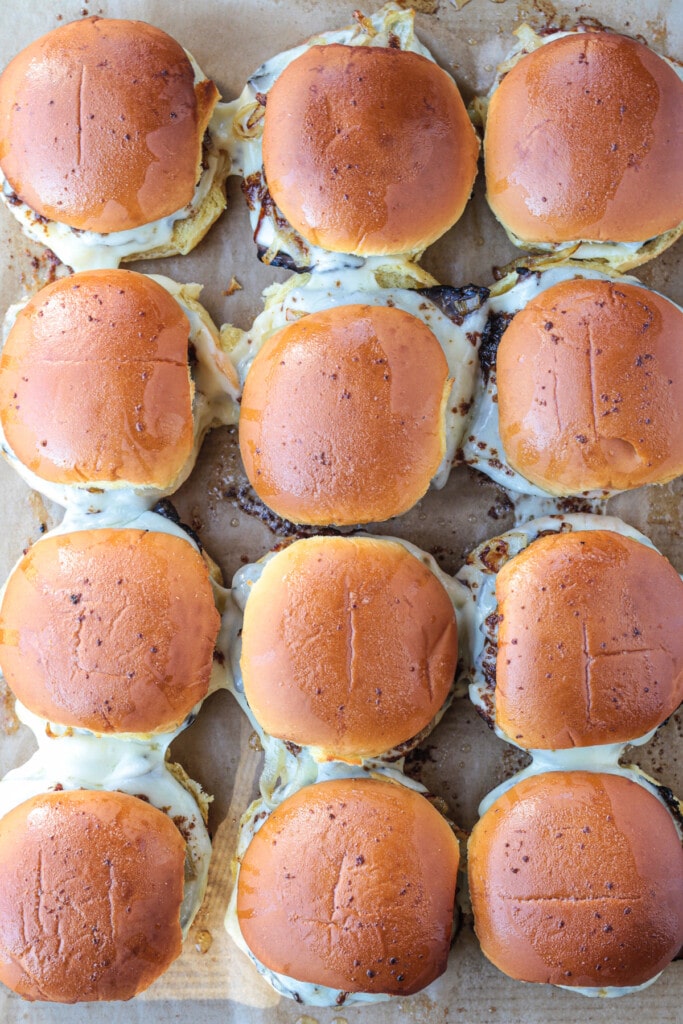 Our French Dip Sliders have a secret sauce that sets them apart from the rest. Beefy, cheesy comfort food perfect for parties and game days! baked sliders on a baking sheet