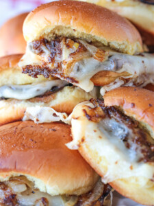 french dip sliders stacked on a plate with napkin in background