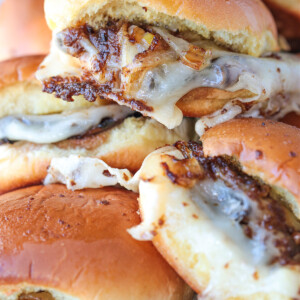 french dip sliders stacked on a plate with napkin in background