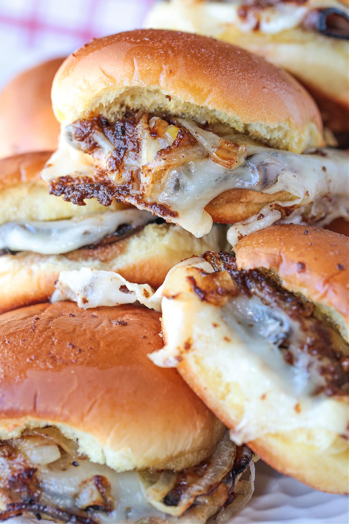 french dip sliders stacked on a plate with napkin in background