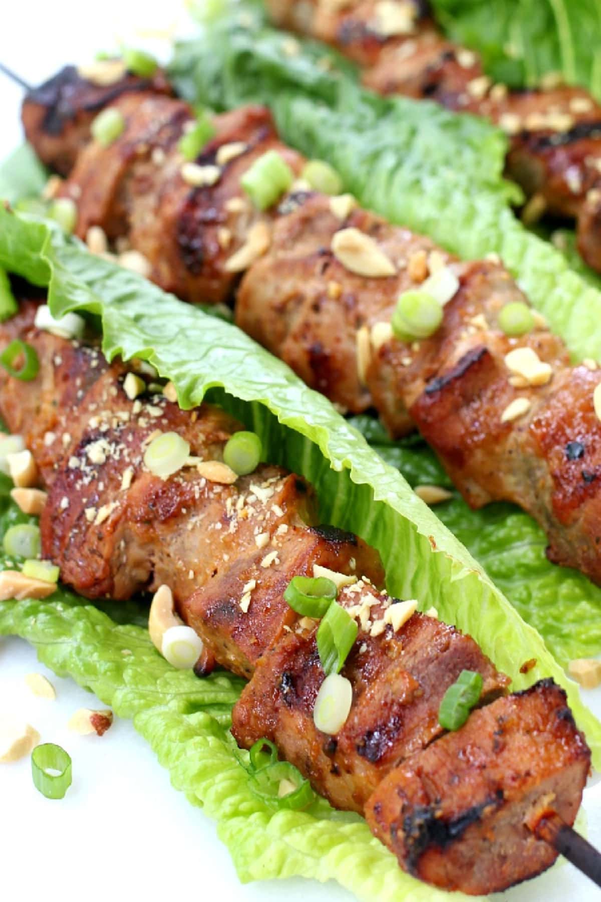 Thai Pork Kabobs have the most delicious sweet and nutty flavor! Wrap in lettuce for easy removal from the skewers and serve with rice! close up of pork kabobs in lettuce leaves
