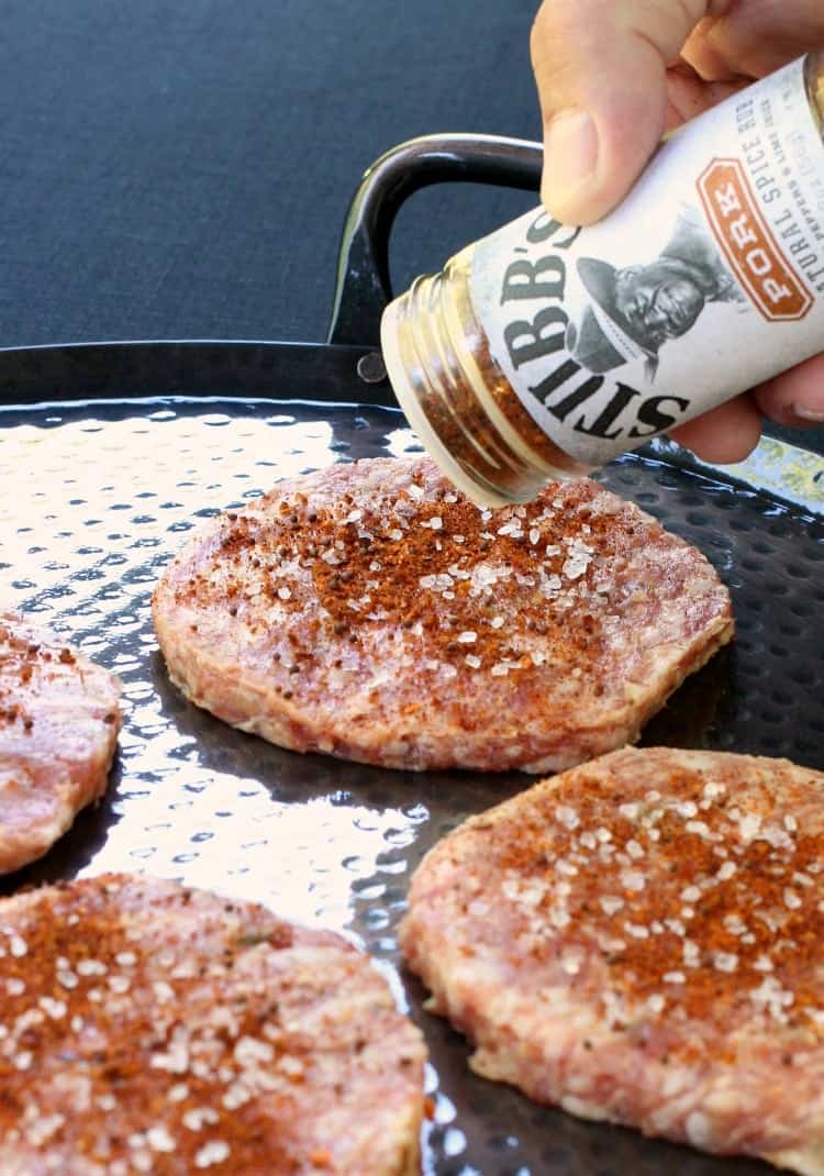 Grab the napkins for this crazy tasty Bang Bang Burger! This pork burger is actually dipped into Bang Bang Sauce before adding to a bun! BBQ Bang Bang Burger patties being seasoned with dry rub