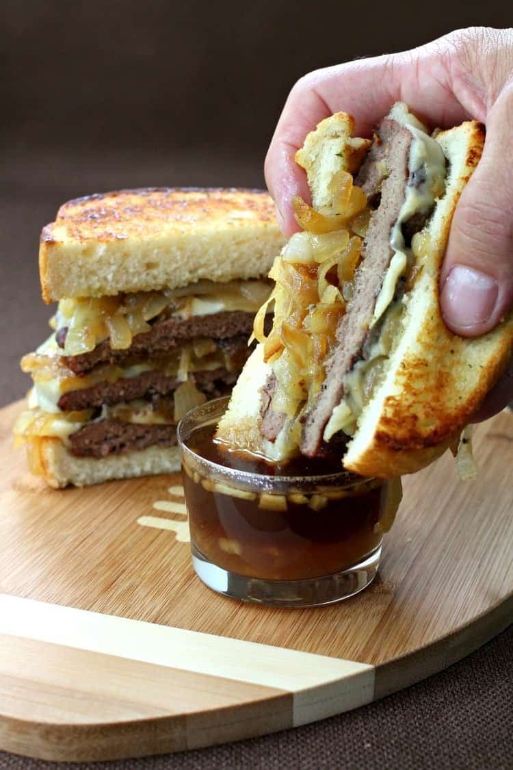 This French Onion Cheeseburger is dripping with gooey cheese and sweet caramelized onions. Serve on Texas toast for an extra flavor boost! French Onion Cheeseburger dipping in juice