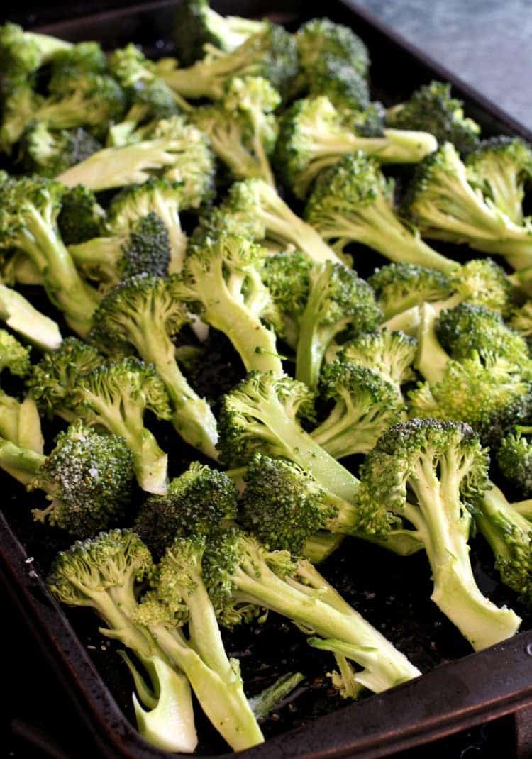 Broccoli spears on a baking sheet with salt and pepper