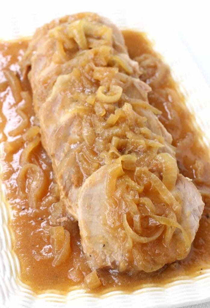 Sliced pork with onion sauce on a white platter