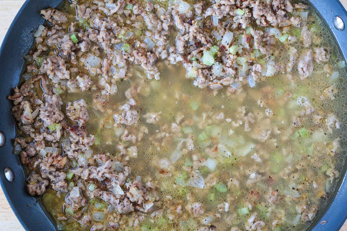 chicken broth in a skillet with sausage and celery