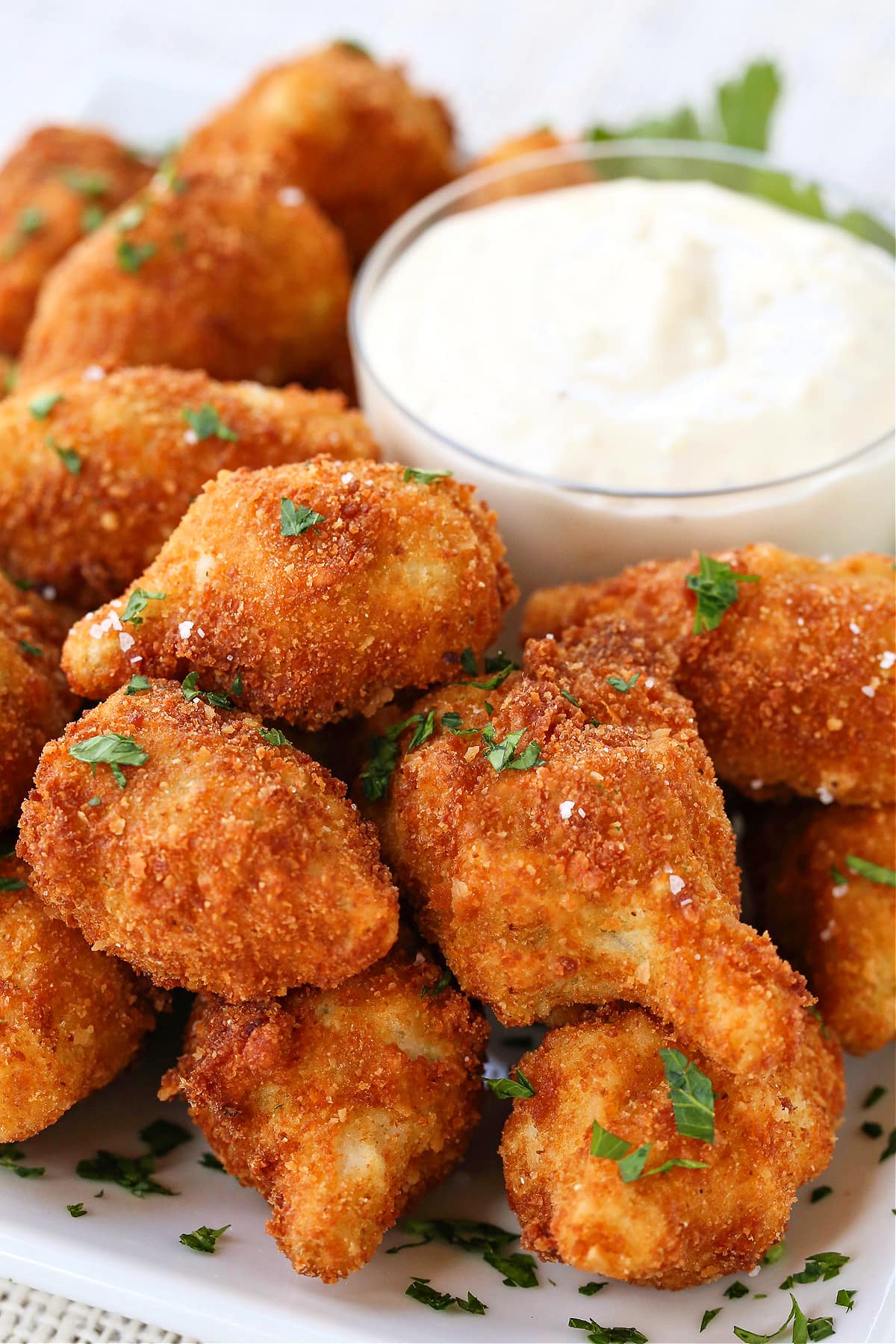 These Fried artichoke hearts are a crispy and addicting appetizer! Make our easy roasted garlic aioli to serve alongside for dipping! fried artichoke hearts on platter with garlic aioli sauce